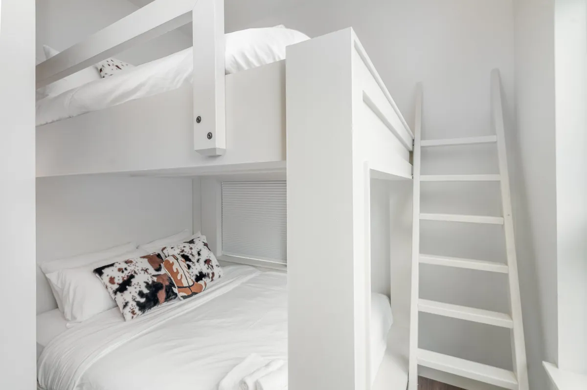 An inviting queen-over-queen bunk bed setup with a textured pillow and a sturdy ladder, exuding a playful yet comfortable vibe that's ideal for families or friends sharing the space.