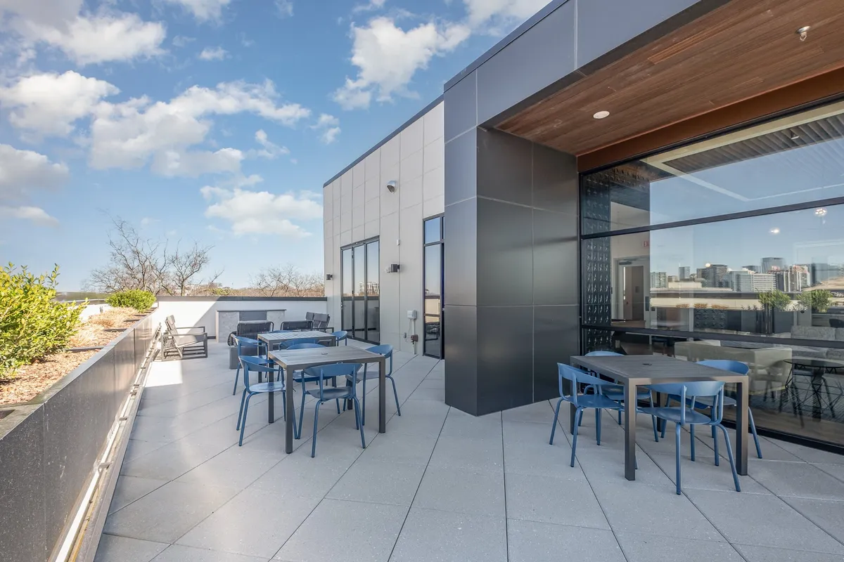 A modern rooftop patio featuring comfortable outdoor seating and stunning views of the city skyline. The atmosphere is relaxed and social, with plenty of space for gatherings and al fresco dining under the open sky.