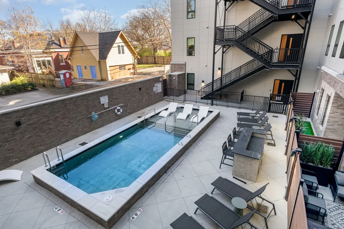 A sparkling outdoor pool framed by lounge chairs and tasteful landscaping, with the building facade in the background. The setting is inviting for swimming, sunbathing, and socializing with neighbors.