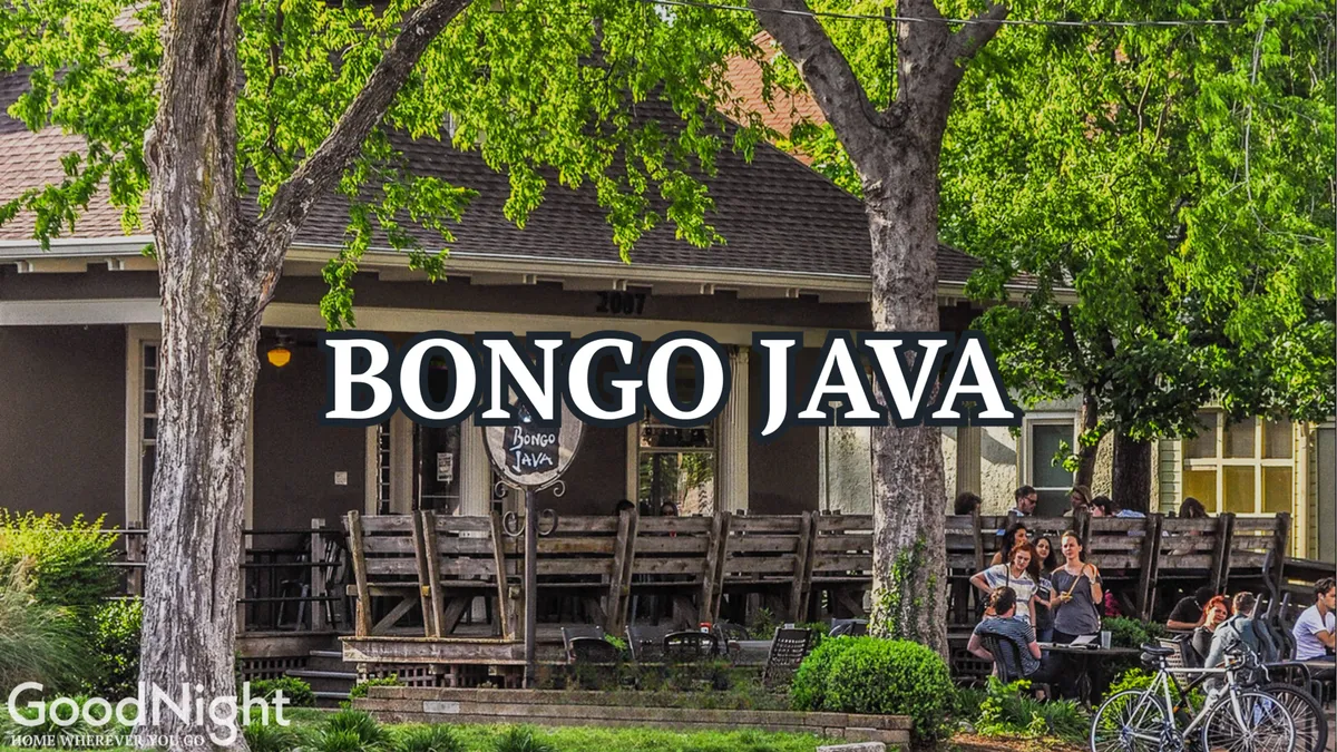 A sun-dappled patio outside Bongo Java features people enjoying coffee under a leafy tree canopy. The lively, communal setting and visible signage create a welcoming neighborhood feel, ideal for strolls and casual meetups.