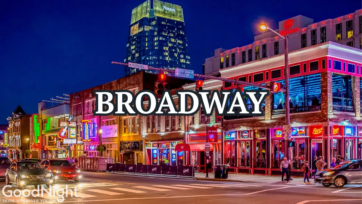 A vibrant nighttime street scene showcasing Nashville’s iconic neon signs, bustling crowds, and lively energy. The image captures people dining, enjoying live music, and experiencing the nightlife along a busy, illuminated thoroughfare.